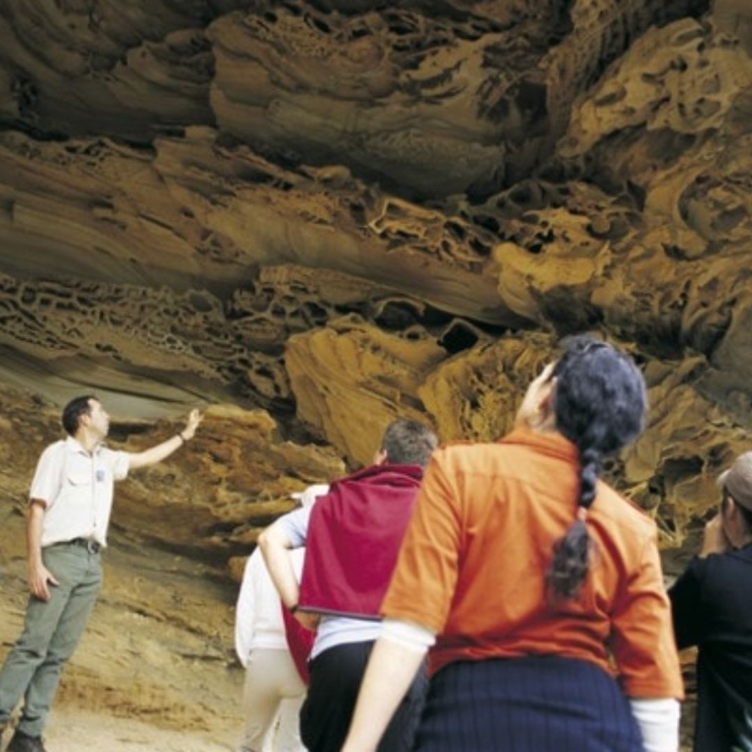 Tourists viewing cave formation with guide from Aboriginal Blue Mountains Walkabout          