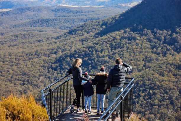 Family group standing on a platform overlooking a vast wide mountainous valley